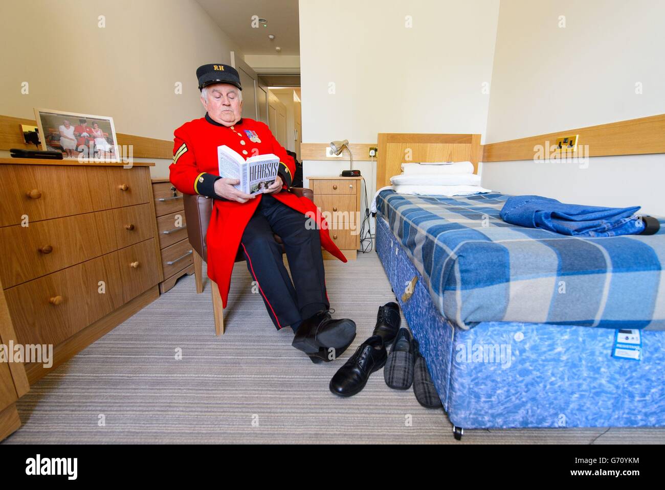 Chelsea Pensioner Tom Mullaney reads in his room on one of the refurbished Long Wards, at the Royal Chelsea Hospital, in Chelsea, west London. Stock Photo