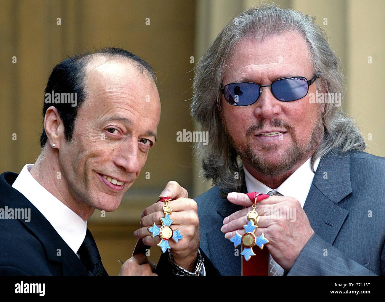 The two surviving members of the Bee Gees, Robin (left) and Barry Gibb hold their CBE's after receiving them from the Prince of Wales at Buckingham Palace, London. The third brother, Maurice Gibb, died last year before he could receive the honour and so his son Adam collected it on his behalf. Stock Photo