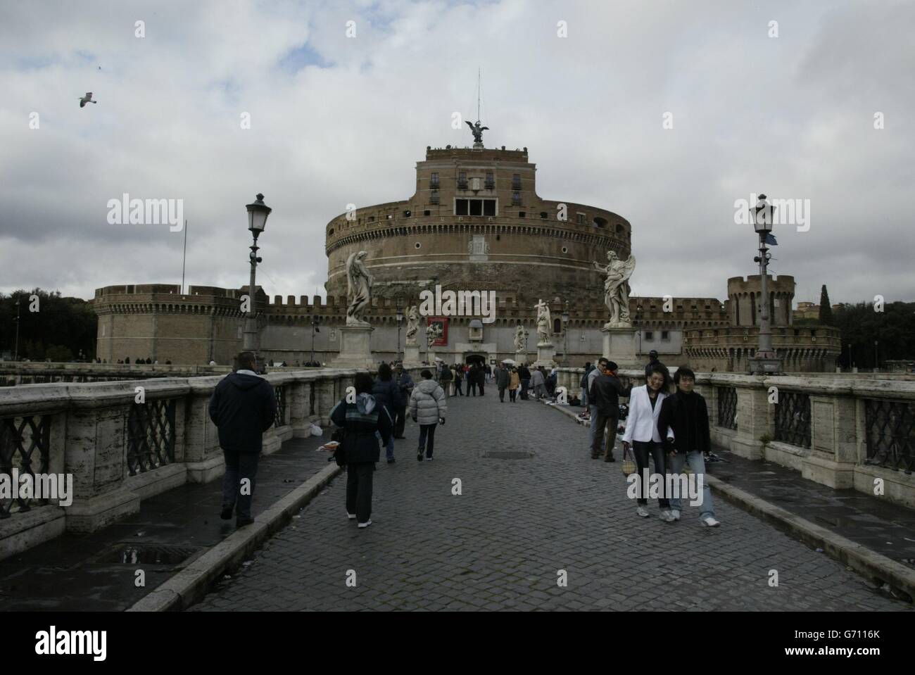 The Castle of the Holy Angel, as Castel Sant'angelo is called, resembles the broken base of a giant goblet. Its immense round mass of stone dominates the Tiber river's mid-city bend. This forbidding fortress was once a marble-faced mausoleum, far larger than the present structure, which Emperor Hadrian had built for himself and succeeding Caesars. There were ranks of colossal statues a sky-hung grove of hemlock trees, a slender central tower, and so on - adornments long ago destroyed. A raised passageway runs all the way from the castle across the Borgo to the Vatican Stock Photo