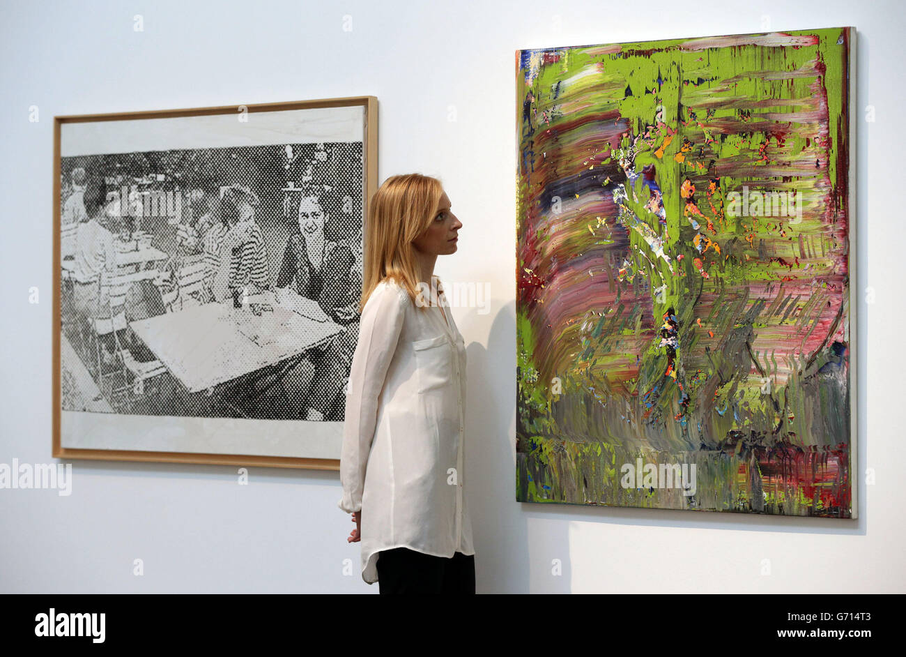 A Christie's employee stood between paintings by Sigmar Polke (left), Biertisch, 1999, and Gerhard Richter, Abstraktes Bild, 1989, during a press view of the Polke/Richter-Richter/Polke exhibition - celebrating Gerhard Richter (b.1932) and Sigmar Polke (1941-2010) by bringing together 65 works from 30 collections to create the artists' first joint show in almost 50 years - at Christie's Mayfair, in London. Stock Photo