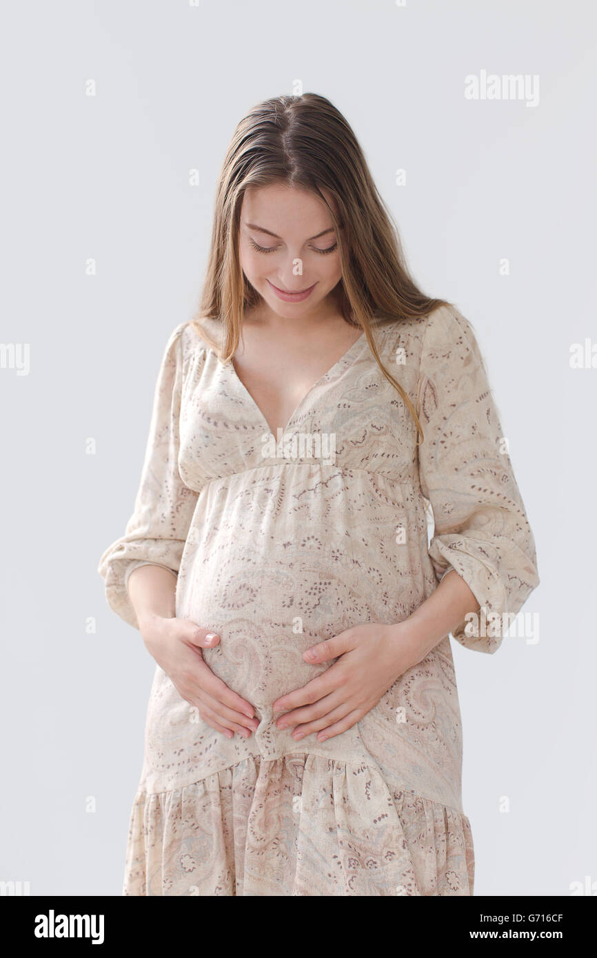 Smiling pregnant woman holding her belly Stock Photo - Alamy