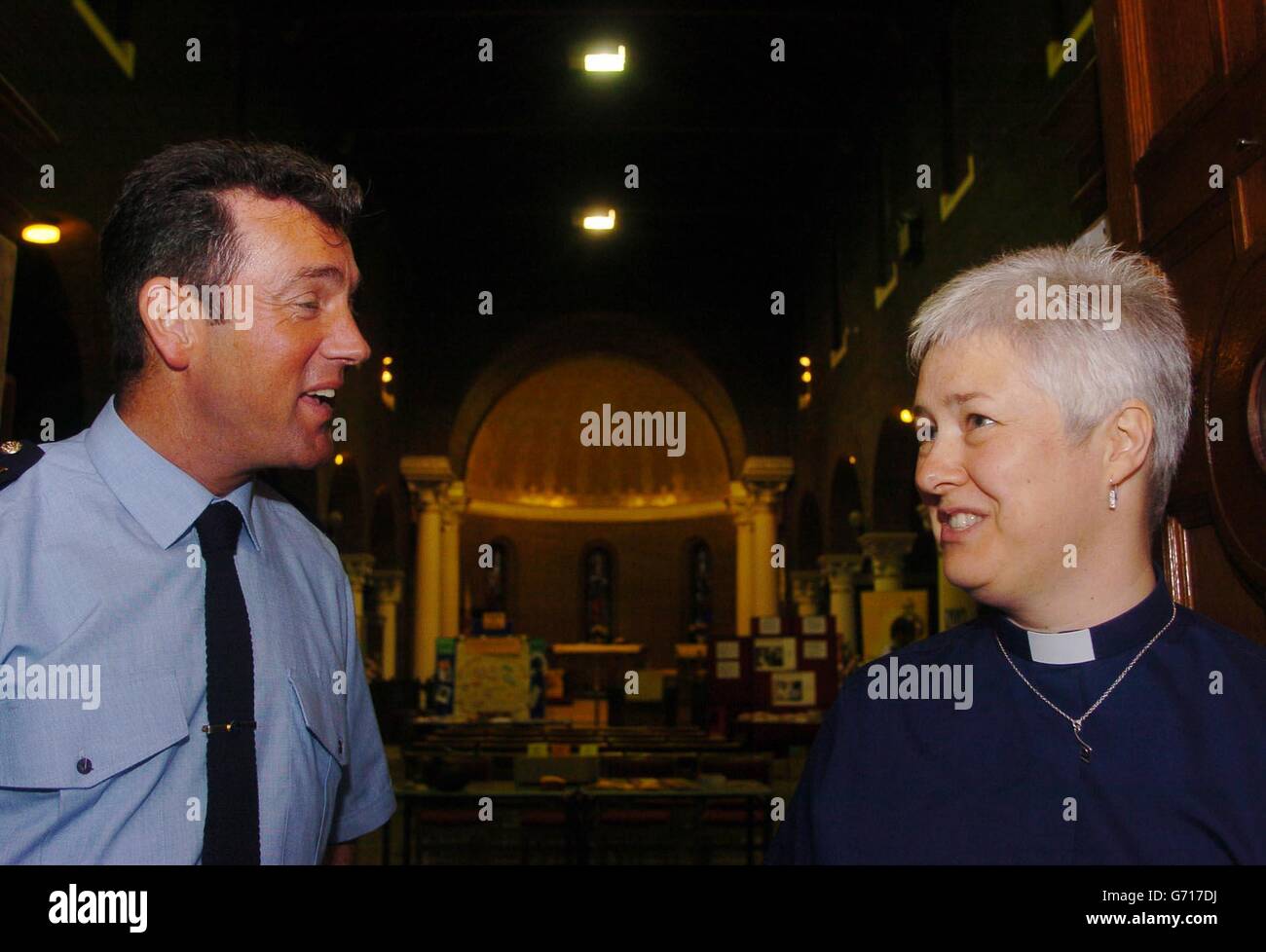 Reverend Katherine Poulton talks with Dave McInerney from Garda Racial & Intercultural Office at The Church of St George & St Thomas on Cathal Brugha Street in Dublin. The Reverend is encouraging immigrants to join her church by hosting various stalls inside the church which look outwards to the far reaches of the world. Stock Photo
