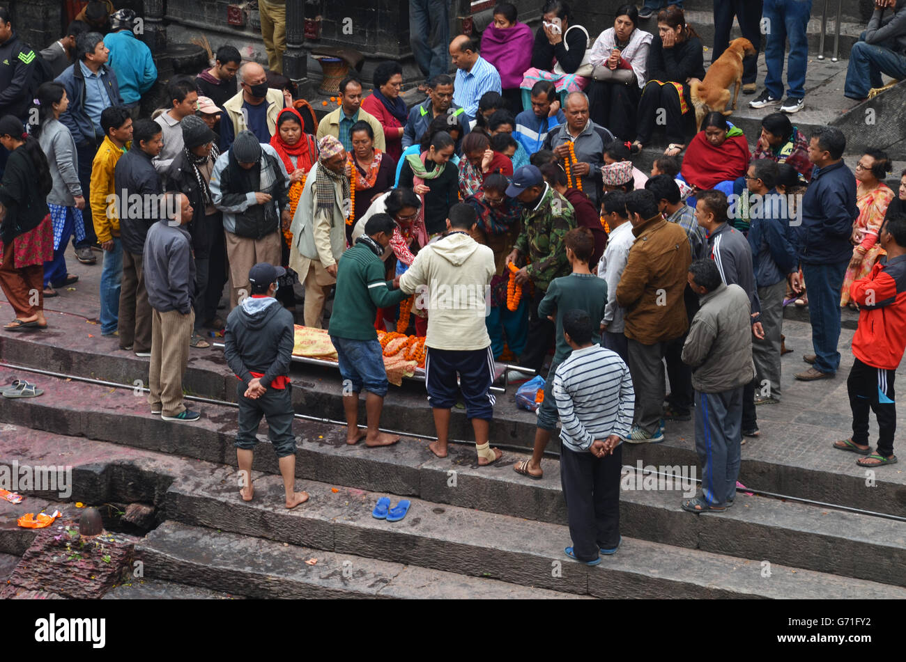Mourners pay their respects to a corpse beside  the Bagmati River near the Pashupatinath Temple in Kathmandu, Nepal Stock Photo