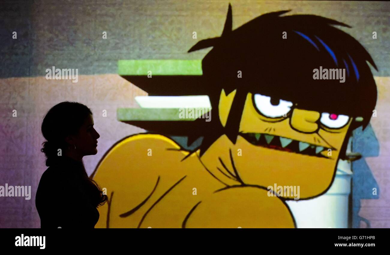 A visitor views artwork for the animated band Gorillaz, by Jamie Hewlett, part of the 'Comics Unmasked - Art and Anarchy in the UK' exhibition at the British Library, London, which runs from May 2 to August 19. Stock Photo