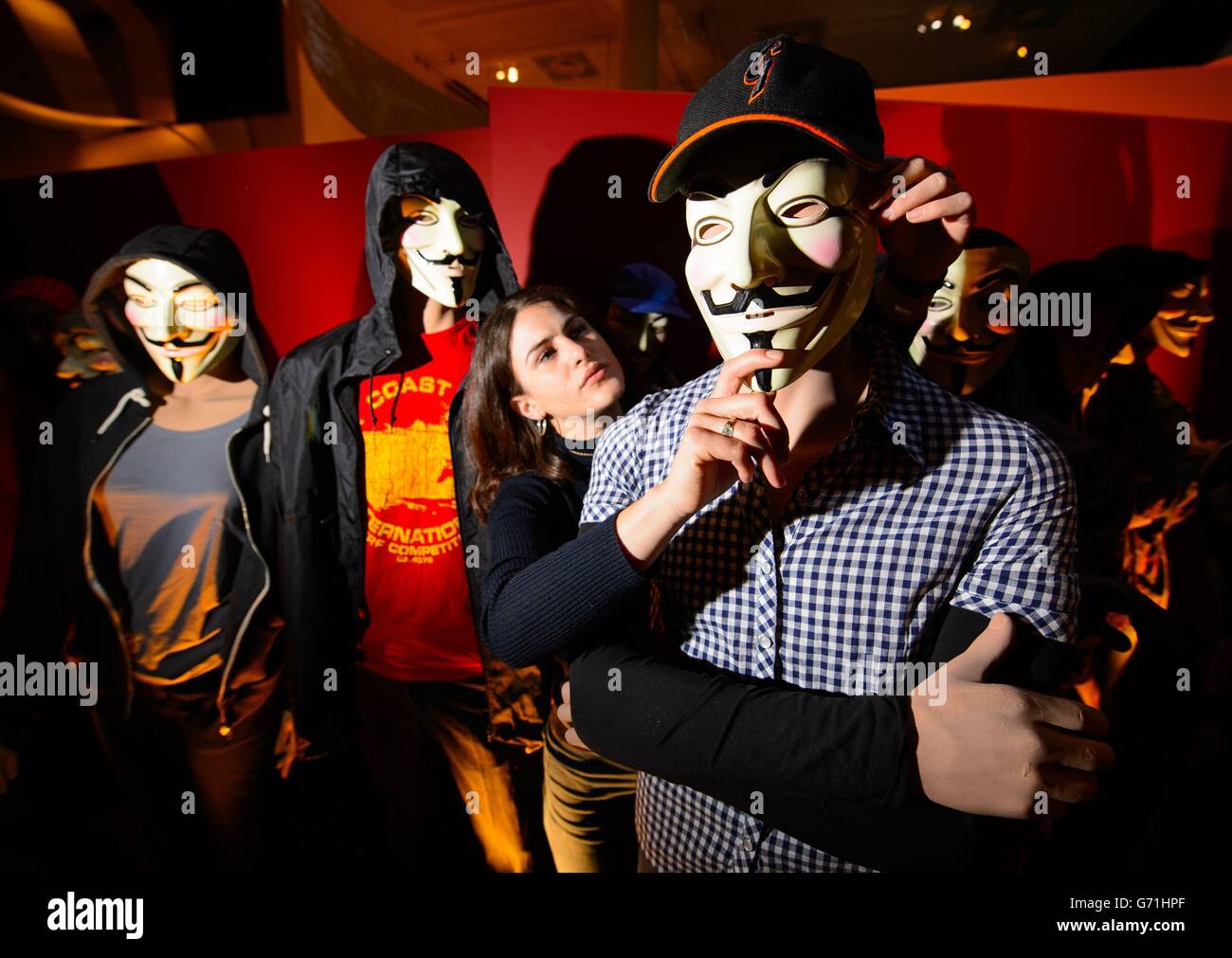 Evie Jeffreys adjusts models wearing masks from the comic 'V for Vendetta', part of the 'Comics Unmasked - Art and Anarchy in the UK' exhibition at the British Library, London, which runs from May 2 to August 19. Stock Photo