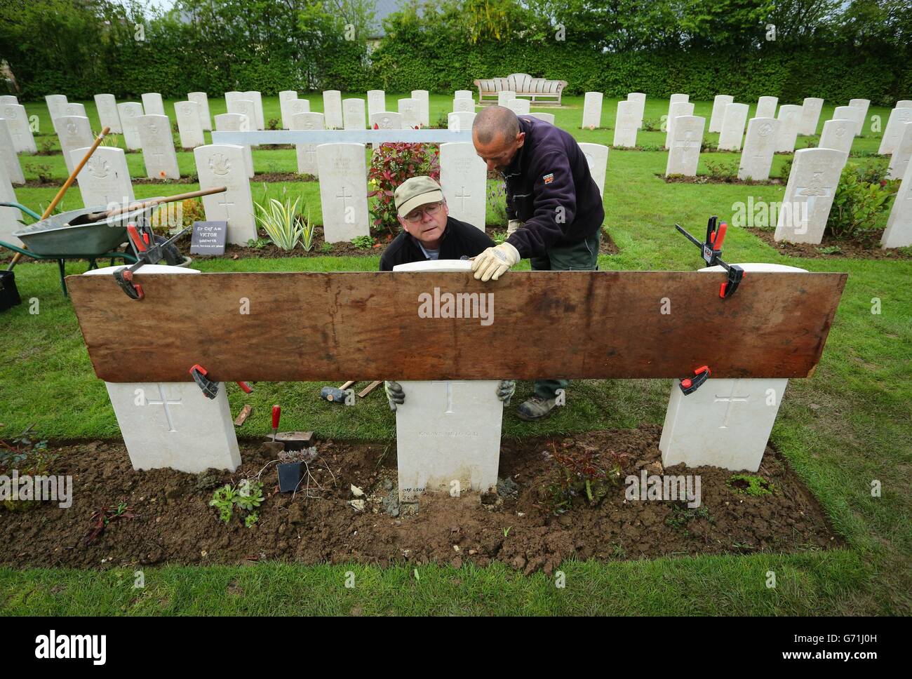 Gardener Caretaker First Class Myles Hunt (left) at the Bayeux War Cemetery in Normandy, with his assistant Jean-Claude Menoux, align the last of just over 4,000 headstones which have been replaced at Bayeux, as the Commonwealth War Graves Commission (CWGC) is working to replace thousands of fallen and damaged headstones at its cemeteries across France and beyond, as it marks both the 70th anniversary of the Normandy landings, and the centenary of the First World War. Stock Photo