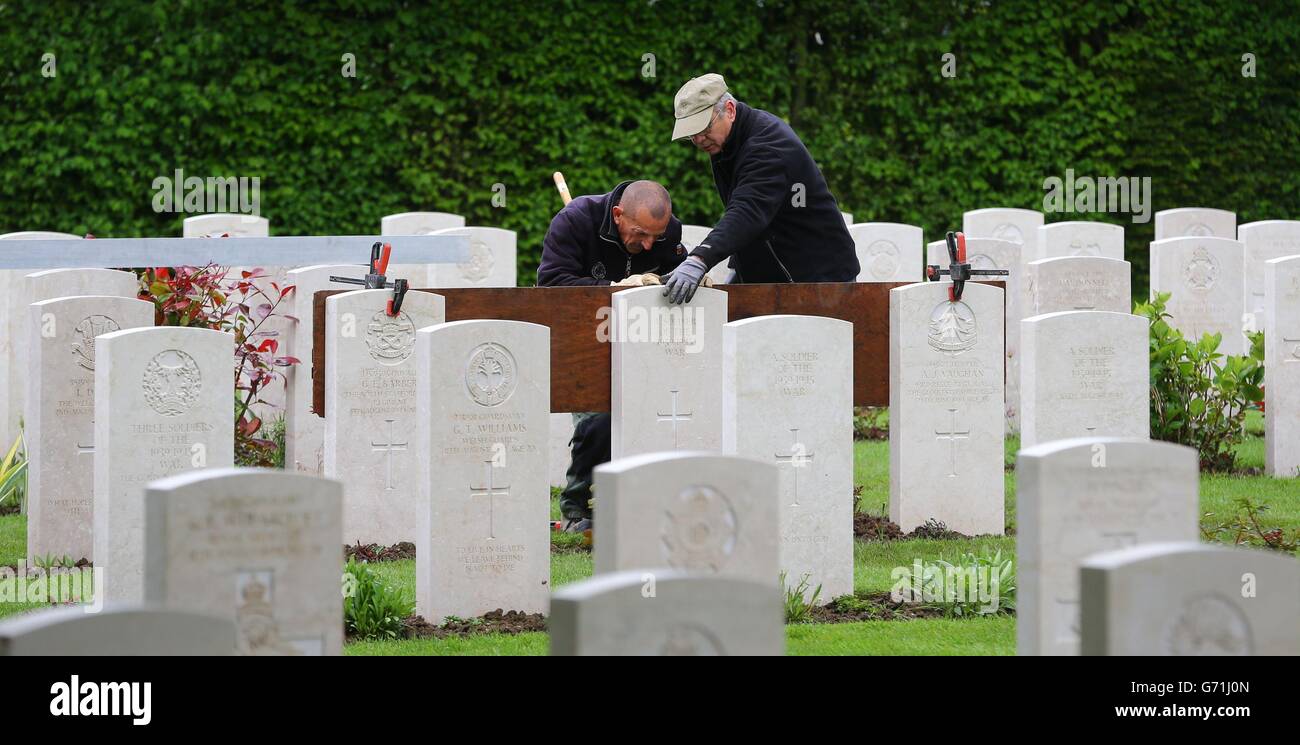 Gardener Caretaker First Class Myles Hunt (right) at the Bayeux War Cemetery in Normandy, with his assistant Jean-Claude Menoux, align the last of just over 4,000 headstones which have been replaced at Bayeux, as the Commonwealth War Graves Commission (CWGC) is working to replace thousands of fallen and damaged headstones at its cemeteries across France and beyond, as it marks both the 70th anniversary of the Normandy landings, and the centenary of the First World War. Stock Photo