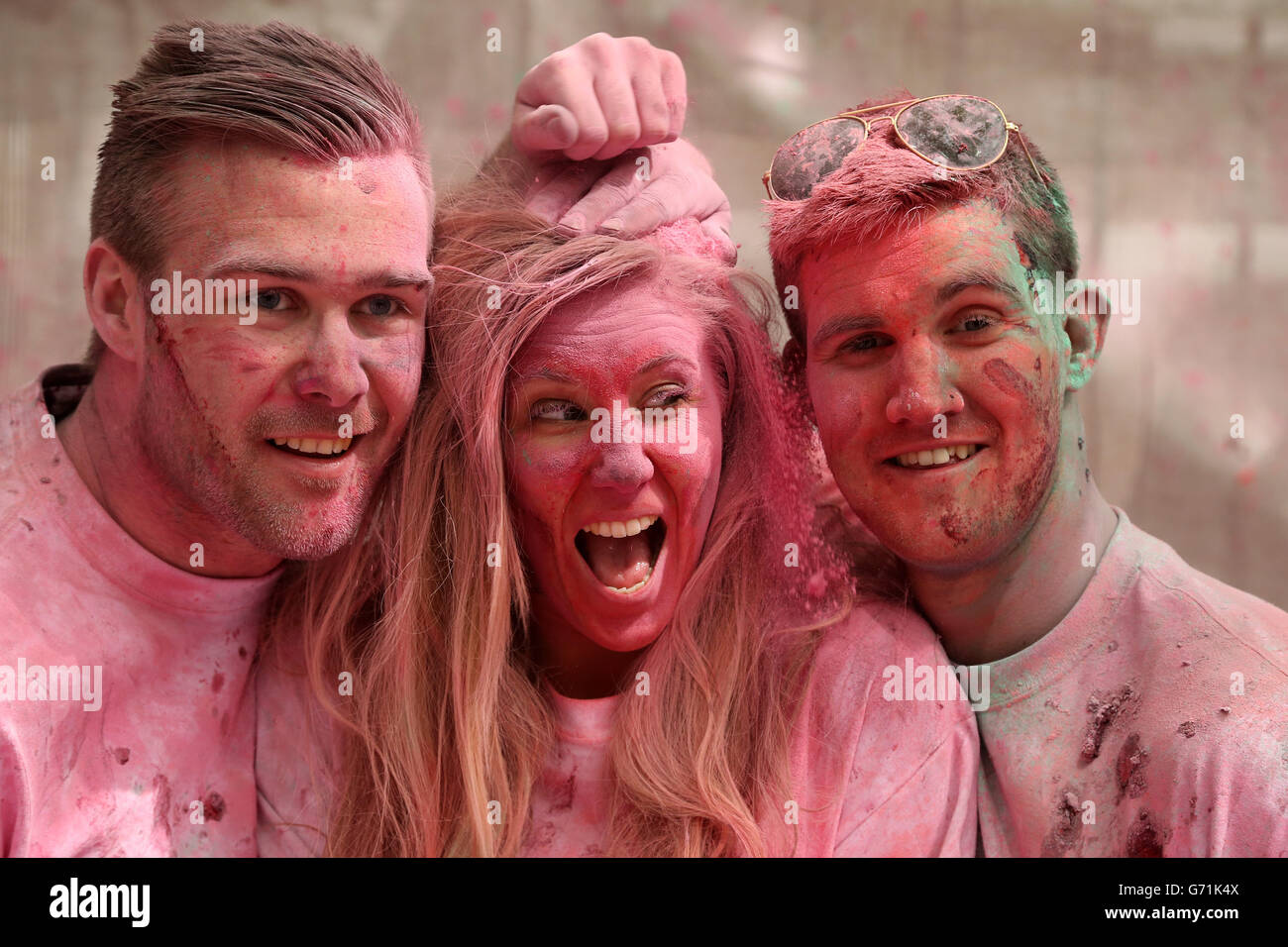 Revellers (from left) Joe Baulf, Charlotte Axe and Mike Payne throw fresh raspberries and powder paint to celebrate the return of Kopparberg Raspberry, at Vibe Bar in Brick Lane, east London. Stock Photo