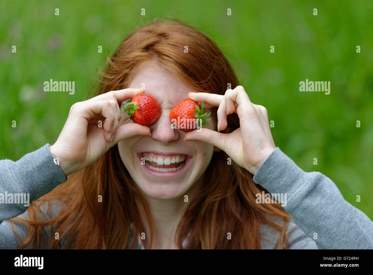 Young girl, female teenager with strawberries in front of the eyes, Bavaria, Germany Stock Photo