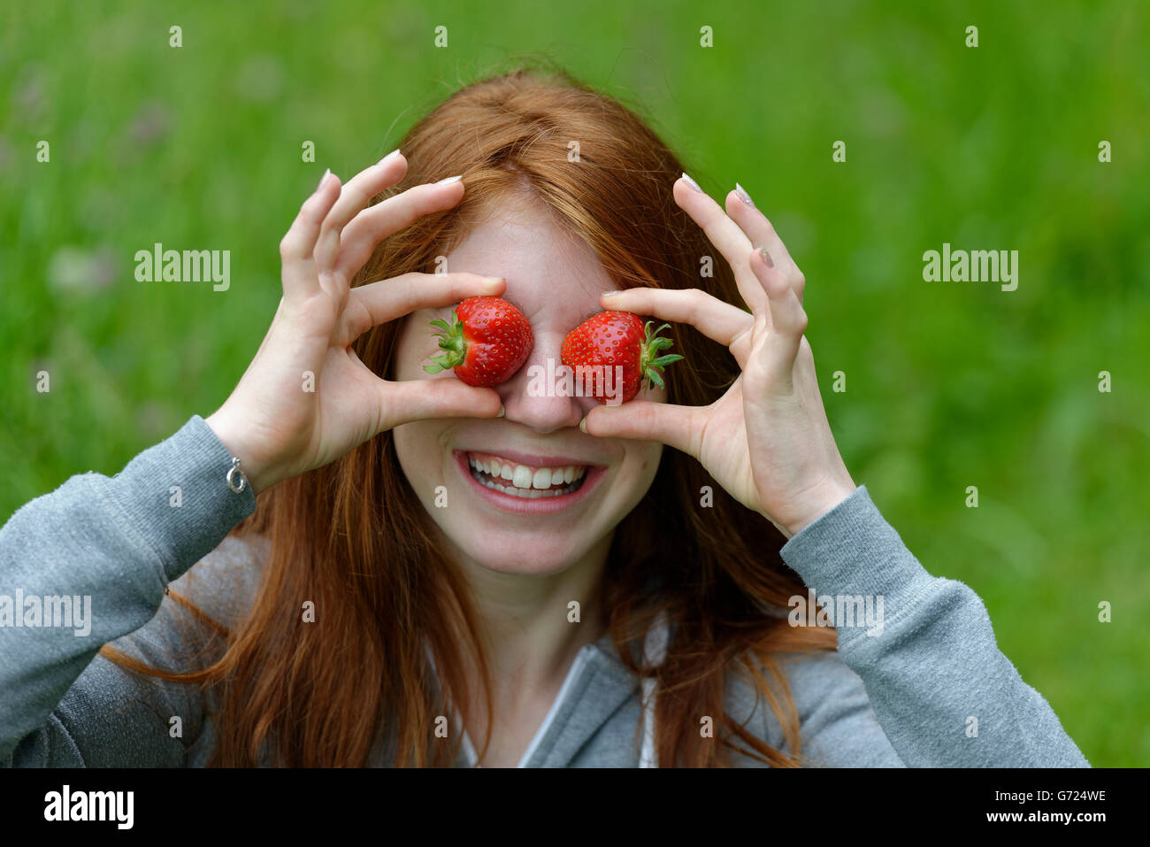 Young girl, female teenager with strawberries in front of the eyes, Bavaria, Germany Stock Photo