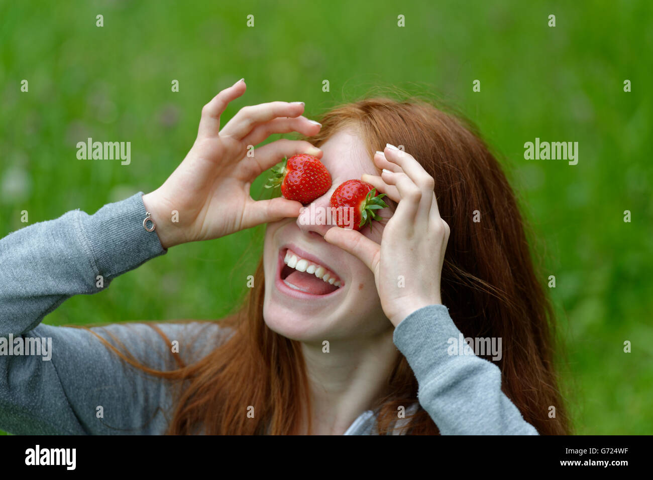 Young girl, female teenager with strawberries in front of the eyes, Bavaria, Germany Stock Photo