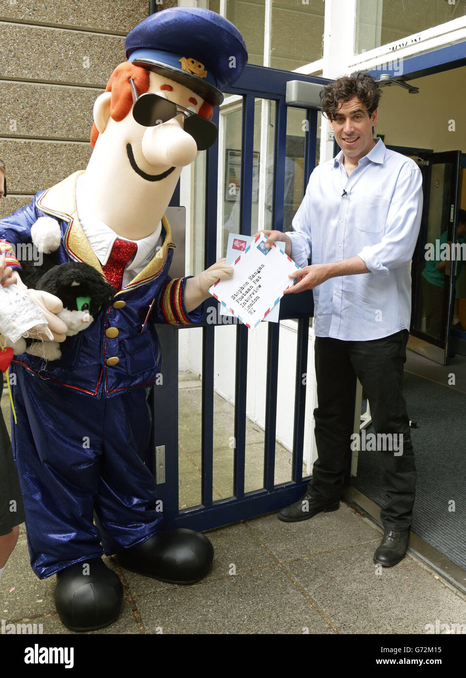 Stephen Mangan (the voice of Postman Pat: The Movie) with Postman Pat during their visit to Sulivan Primary School, in London. Stock Photo
