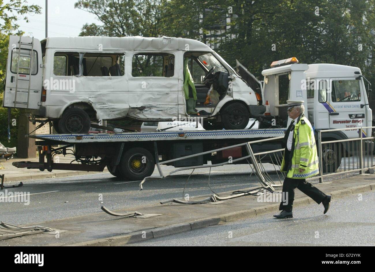 A vehicle transporter carries away the minibus, thought to have beeen carrying Chinese cockle-pickers, which was in collision with a lorry in Bootle, Merseyside. Fourteen ambulances were called to the scene just after 5 am and 16 people are being treated for the injuries they received. Stock Photo