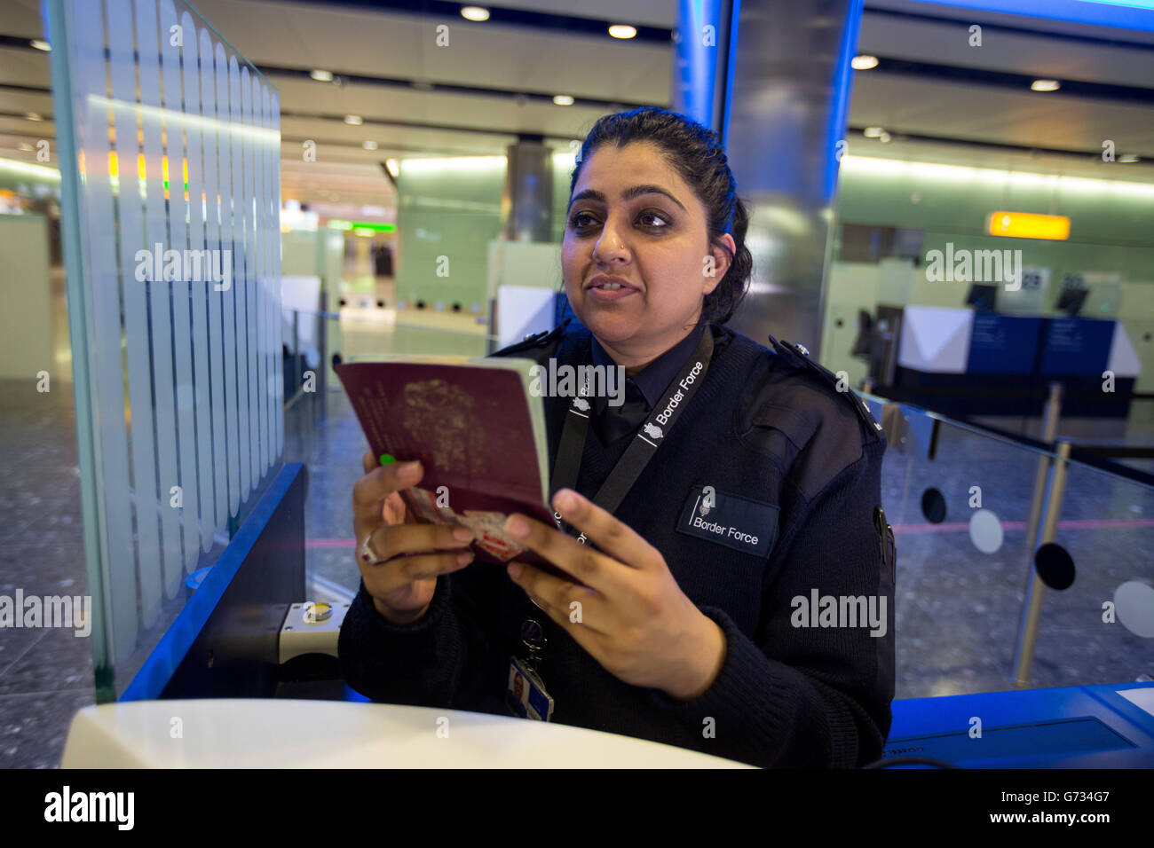 A Border Force officer checks passports of arrival passengers in