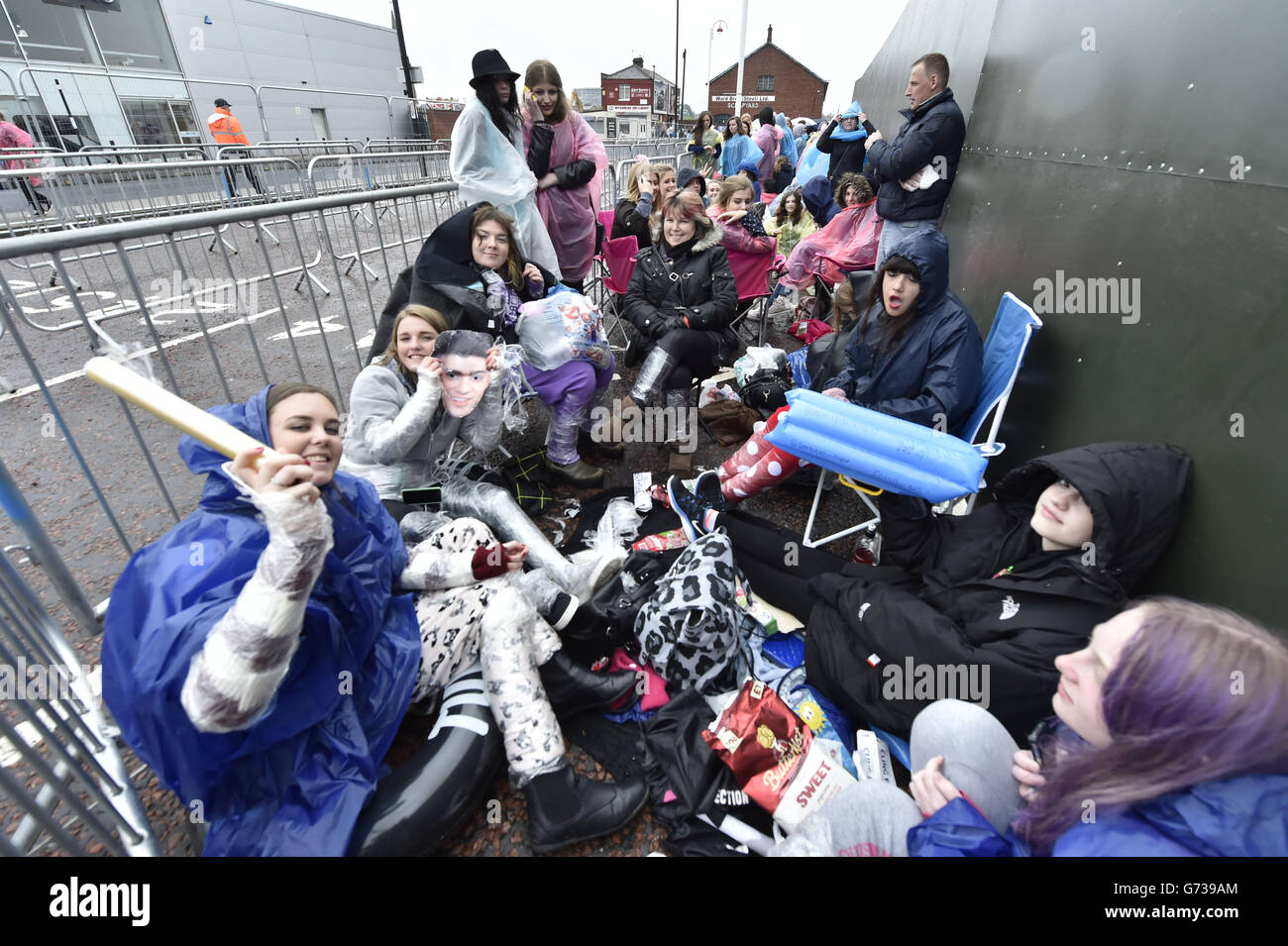 Fans of One Direction wait outside in the rain ahead of their concert ...