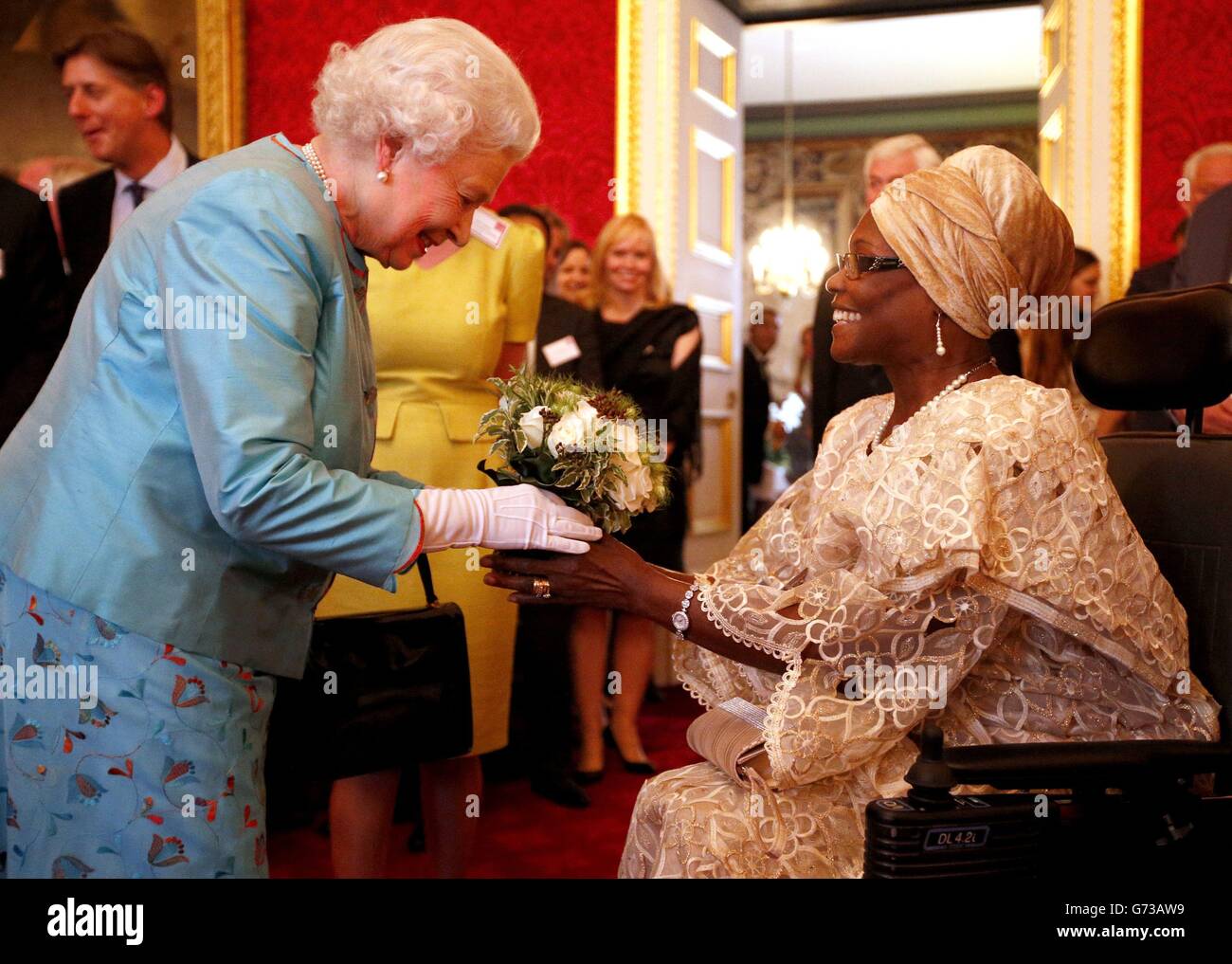 Queen Elizabeth II receives flowers from Veronica Thomas during a reception for Leonard Cheshire Disability in the State Rooms, St James's Palace, London. Stock Photo