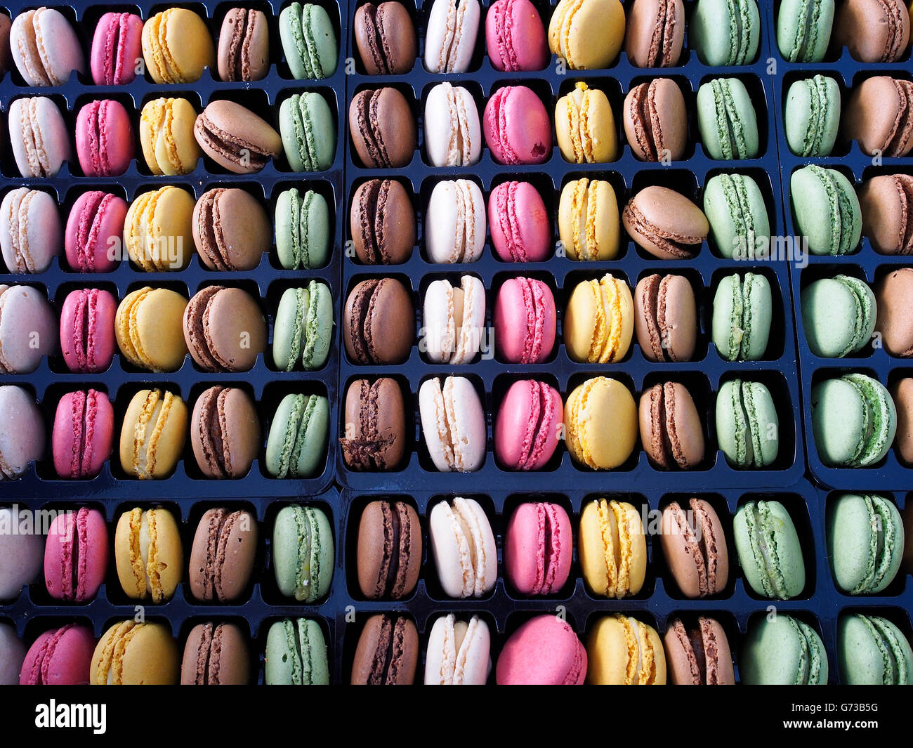 Rows and columns of multicolored macarons, traditional French cookies ...