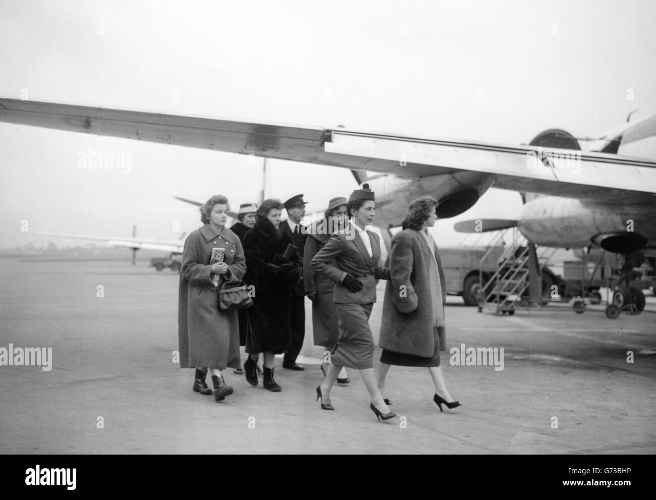 Wives of Manchester United players injured in the plane crash at Munichare pictured at Manchester Airpost before they fly to Munich. Leading the group, accompanied by an air stewardess is Mrs. Hilda Berry, wife of outside right Johnny Berry and mother of three boys. Behind her are Mrs. Viollet (wife of Dennis Viollet), Mrs. Betty Wood (wife of Ray Wood), Mrs Jean Blanchflower (wife of Jackie Blanchflower), and Mrs. Jane Scanlon (wife of Albert Scanlon). Stock Photo