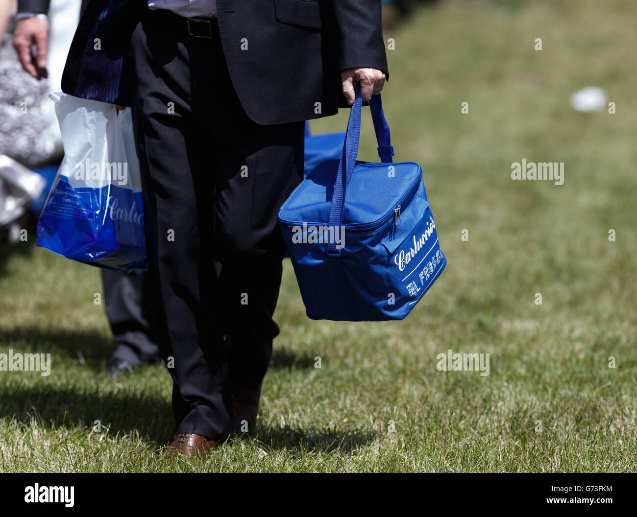 Horse Racing - Investec Ladies Day 2014 - Epsom Downs Racecourse. A racegoer carries a picnic hamper Stock Photo