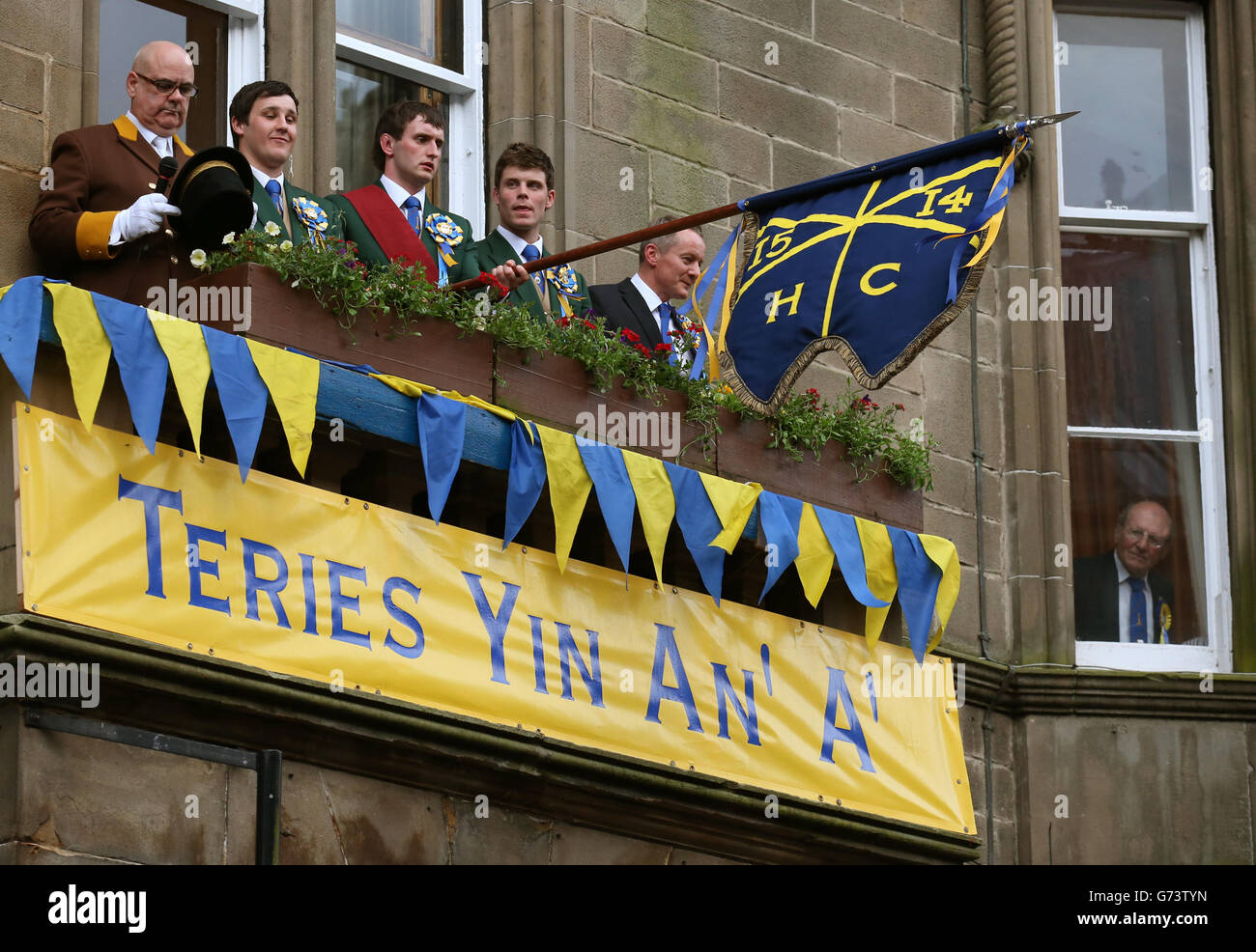 Cornet Ross Gibson waves the flag from the town hall after the Colour Bussing during Hawick Common-Riding in Hawick, Scotland. Stock Photo