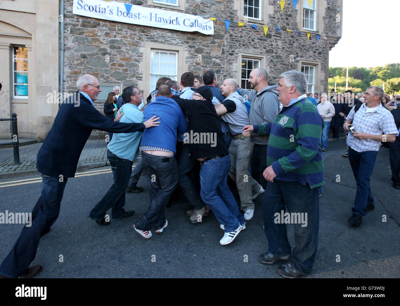 People try to wrestle the Rams Horn during Snuffin' by the Auld Brig during Hawick Common-Riding in Hawick, Scotland. Stock Photo