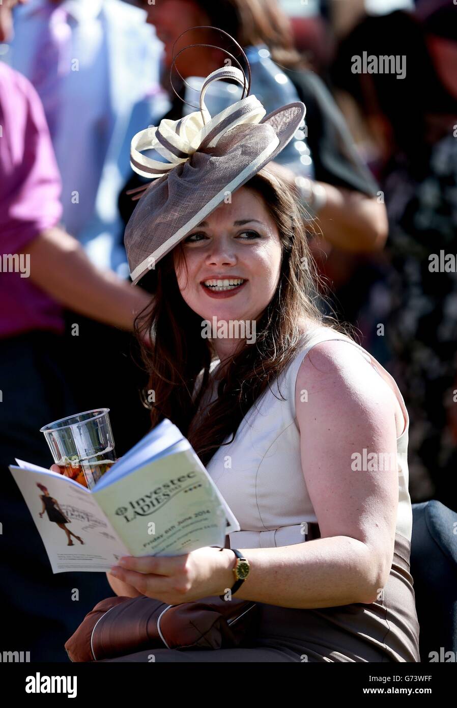 Horse Racing - Investec Ladies Day 2014 - Epsom Downs Racecourse. A race goer enjoys the racing during Investec Ladies Day at Epsom Downs Racecourse, Surrey. Stock Photo