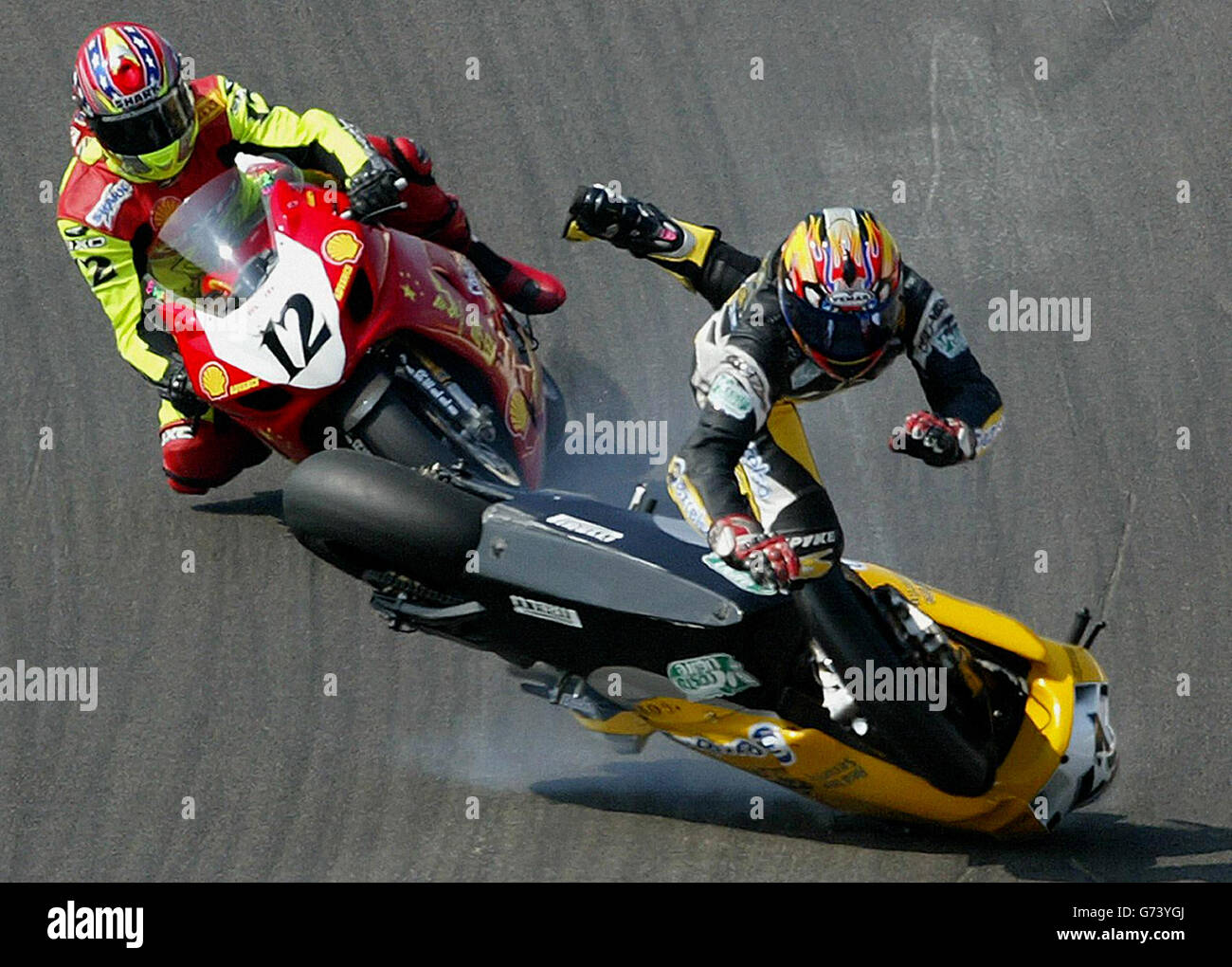 Italy's Giancarlo DeMatteis crashes badly and is narrowly missed by Warwick Nowland (12) during the second of the day's races on round 8 of the SBK World Superbike Championships at Brands Hatch. 01/08/2004 Picture: Gareth Fuller/PA Photos Stock Photo
