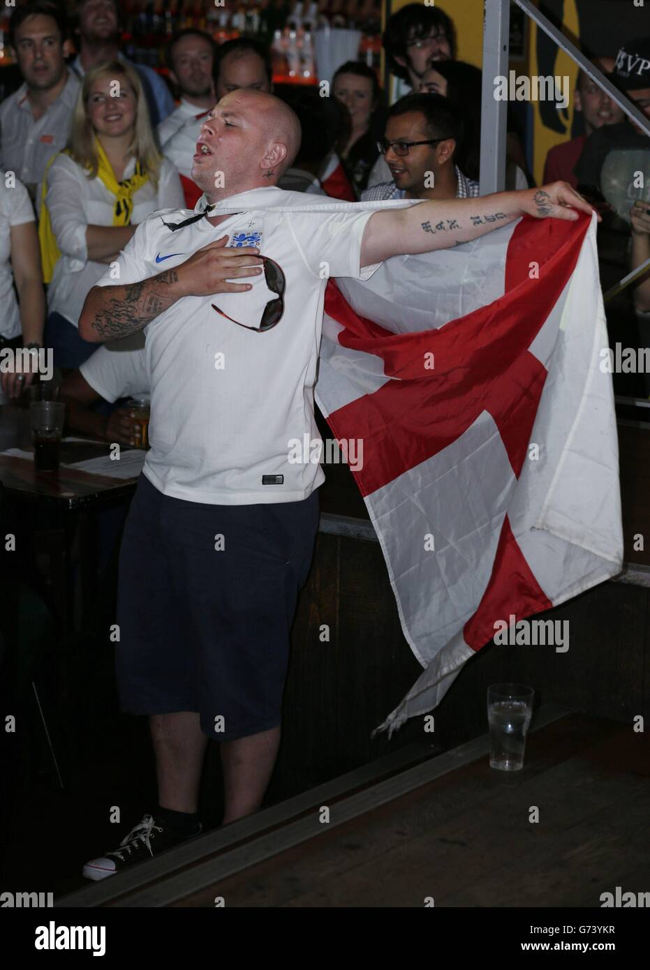 A man sings the national anthem before supporters in the Walkabout Temple, Temple Place in central London watch the England v Italy Group Stage game in the 2014 Fifa World Cup in Brazil. Stock Photo