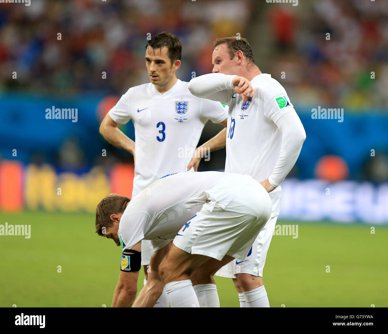 England's Leighton Baines and England's Wayne Rooney stand nearby as England's Steven Gerrard places the ball for a free kick during the FIFA World Cup, Group D match at the Arena da Amazonia, Manaus, Brazil. PRESS ASSOCIATION Photo. Picture date: Saturday June 14, 2014. See PA story SOCCER England. Photo credit should read: Mike Egerton/PA Wire. Editorial use only. No commercial use. No use with any unofficial 3rd party logos. No manipulation of images. No video emulation Stock Photo