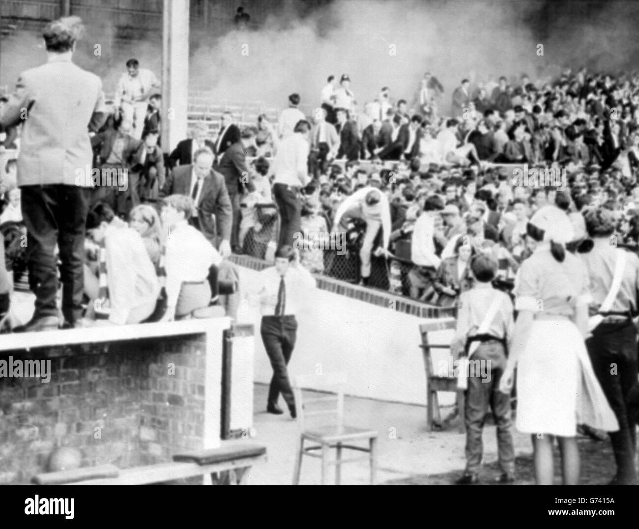 As smoke rises in clouds, spectators are evacuated from the main stand at the Nottingham Forest ground where the First Division match against Leeds United was abandoned at half time. Stock Photo