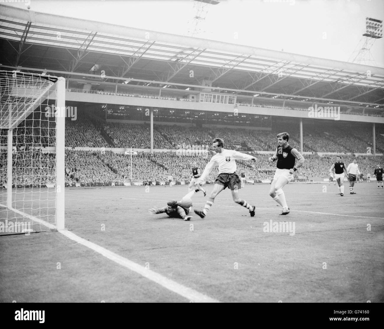 Preston outside-left Holden boots the ball past the fallen West Ham keeper Standen to score the first goal of the FA Cup Final at Wembley. Looking on (right) is West Ham right back Bond. Preston held their lead for only sixty seconds, Sissons equalising. Stock Photo