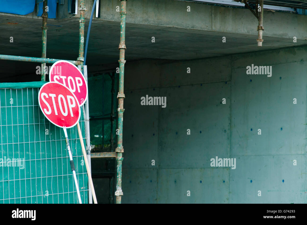 Stop signs resting on some scaffolding at a driveway entrance to a construction site Stock Photo