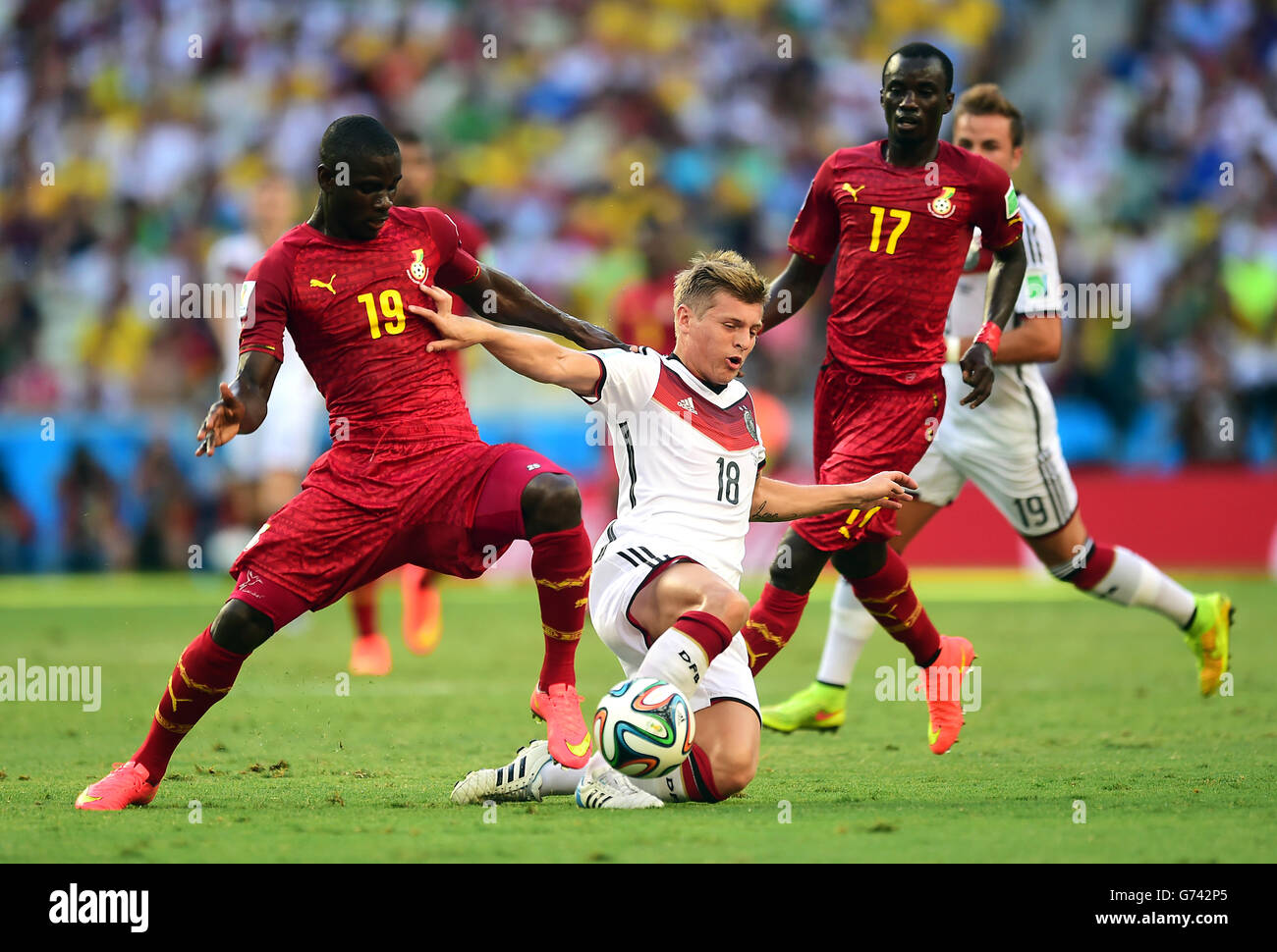 Germany's Toni Kroos is tackled by Ghana's Jonathan Mensah (left) as Ghana's Mohammed Rabiu (right) looks on Stock Photo