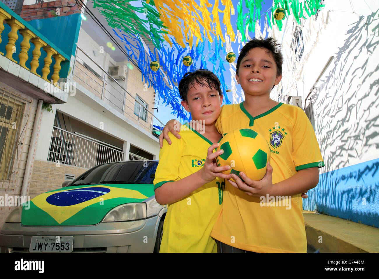 Young locals hold a football in the streets of Manaus before the FIFA World Cup, Group D match at the Arena da Amazonia, Manaus, Brazil. Stock Photo