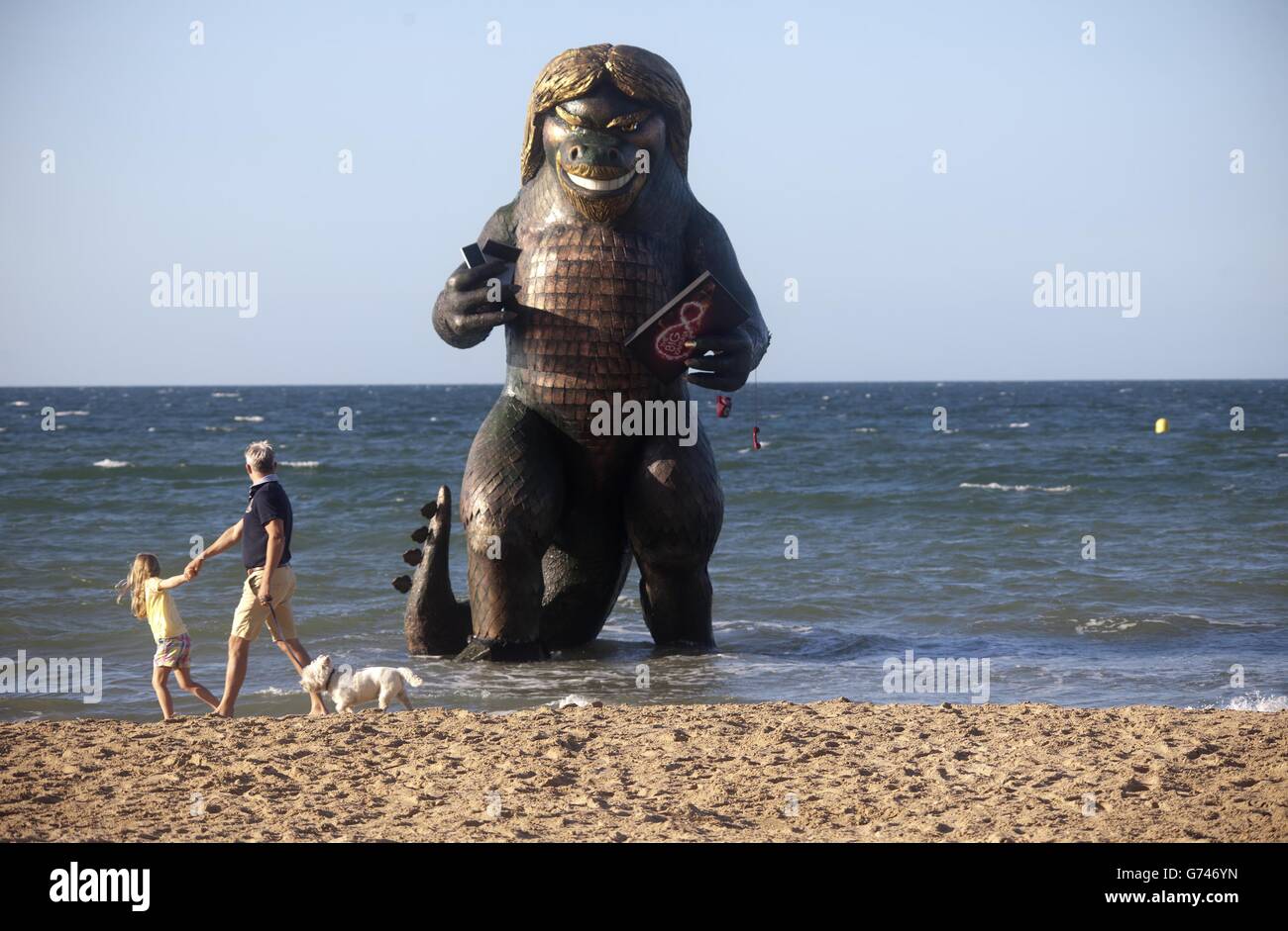 A 25 foot high sea creature resembling Richard Branson emerges from the sea on Bournemouth beach in Dorset carrying a TV, laptop, phone and mobile to celebrate the launch of Virgin Media's Big Kahuna quad-play bundle. Stock Photo