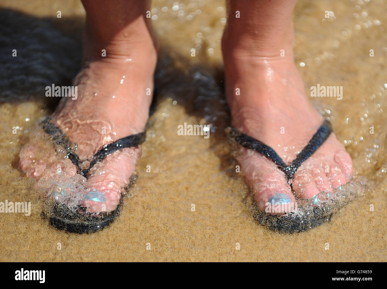 Generic stock photo of feet in flip flops on the beach at Praia da Luz