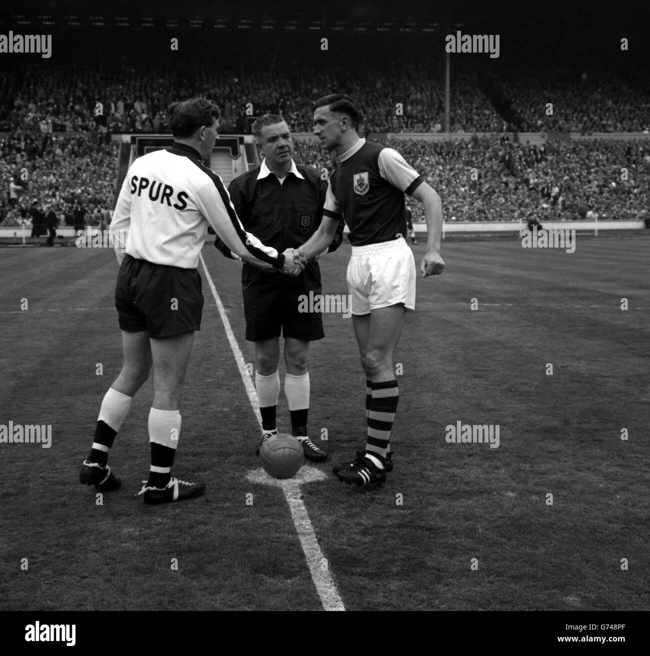The two Captains, Danny Blanchflower of Tottenham Hotspurs (left) and Jimmy Adamson of Burnley, both righ-halves, shake hands before the kick-off in the FA Cup final at the Empire Stadium, Wembley. Centre is the referee, Mr J Finney of Hereford Stock Photo