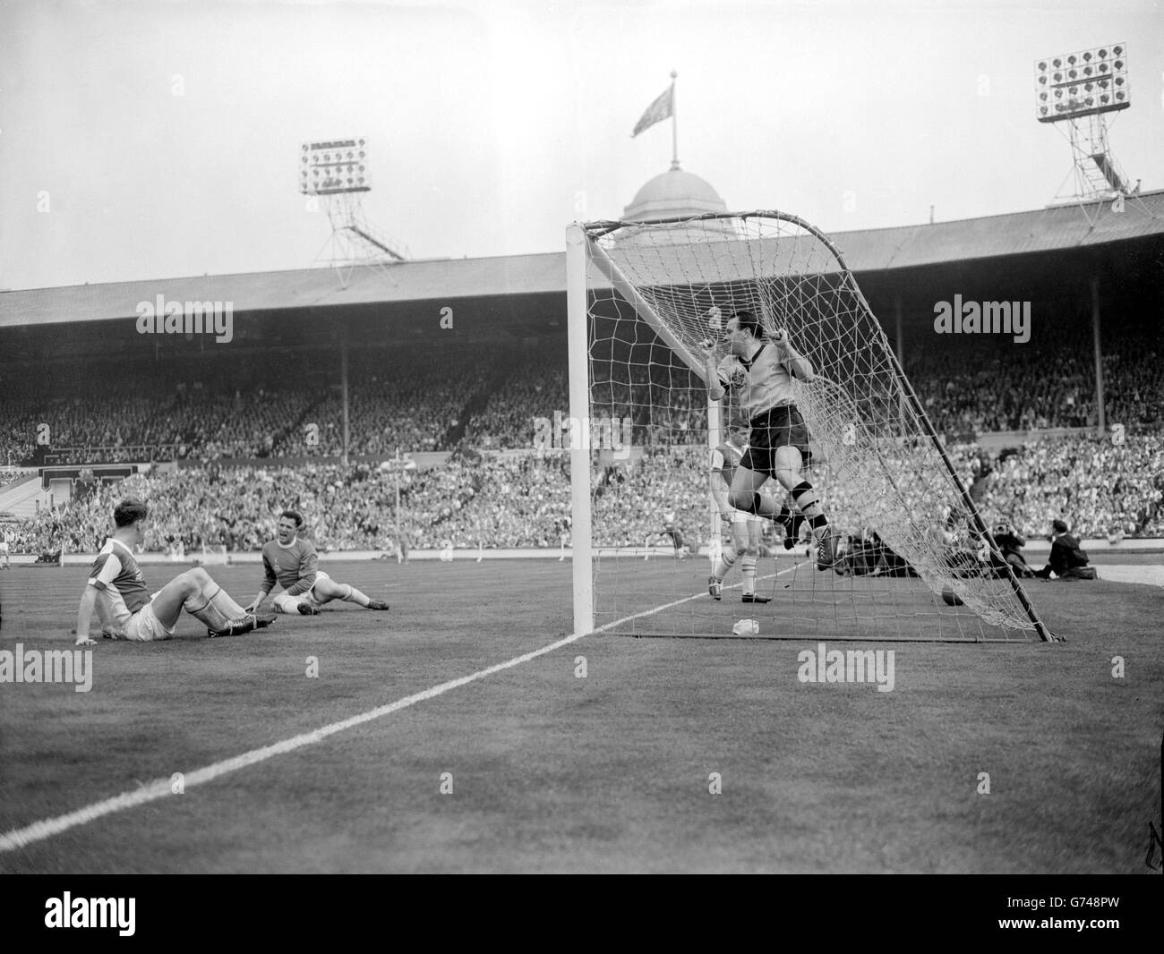 Wolves outside right, Deeley hangs jubilantly on the netting after chasing an 'own goal' over the line while outside the goal Blackburn keeper Leyland (centre) and left half McGrath, the scorer, seem to be holding a sit down enquiry. Disconsolate Blackburn left back Dave Whelen goes in to pick up the ball. He later broke his leg and was taken to hospital. This incident opened the scoring for Wolves and they went on to win 3-0. Stock Photo