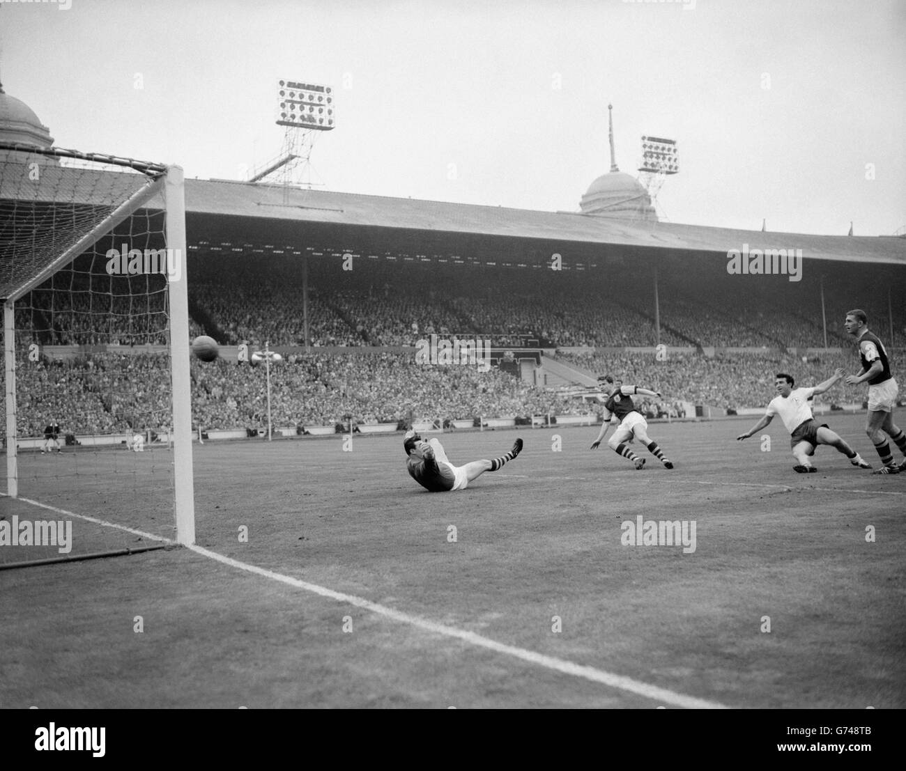 As Burnely goalkeeper Adam Blacklaw rocks helplessly on the turf, the ball sails into the net for Tottenham Hotspur's second goal - it was scored by centre-forward Bobby Smith (white shirt, right) - in the FA Cup Final at the Empire Stadium, Wembley. This goal put Spurs 2-1 ahead, and they wwere leading for the second time in the match. They won 3-1 to retain the cup. Stock Photo