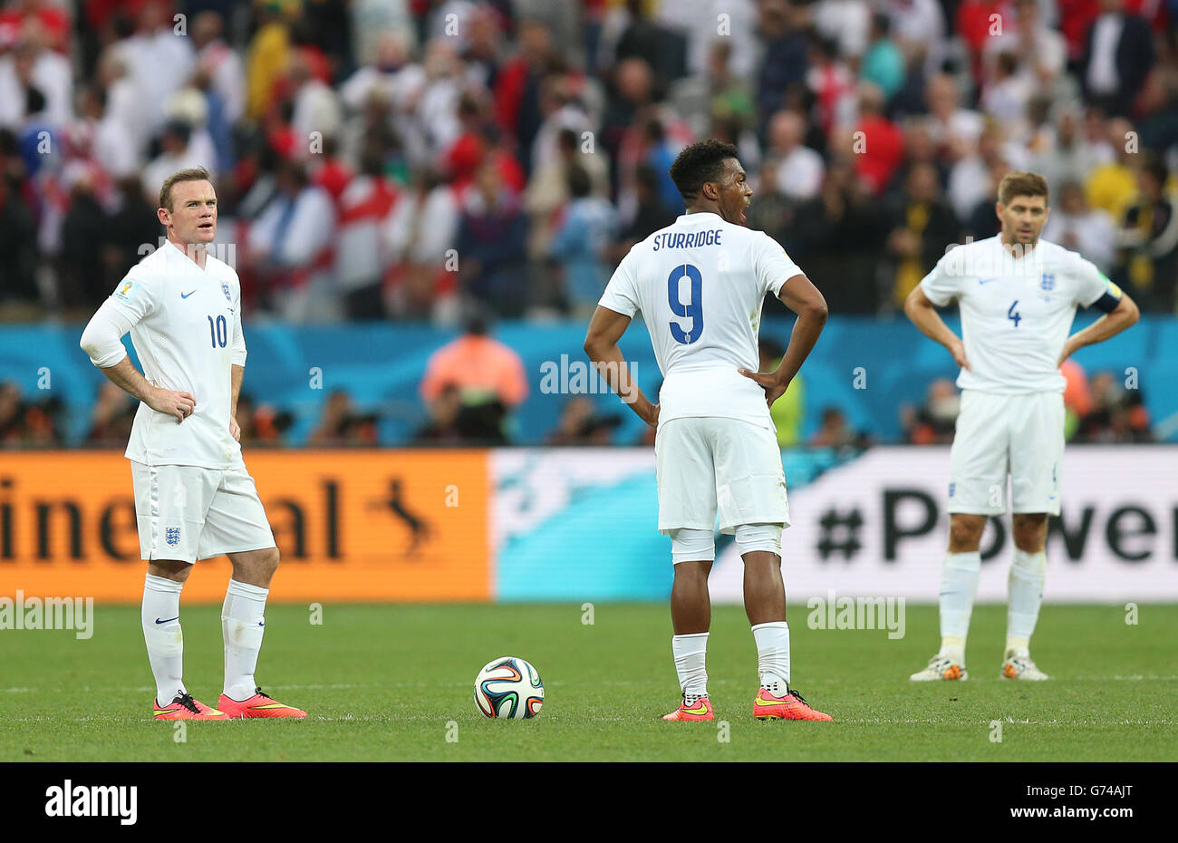 England's Wayne Rooney (left), Daniel Sturridge (centre) and Steven Gerrard stand dejected after Uruguay's Luis Suarez celebrates scoring the first goal during the Group D match the Estadio do Sao Paulo, Sao Paulo, Brazil. Stock Photo
