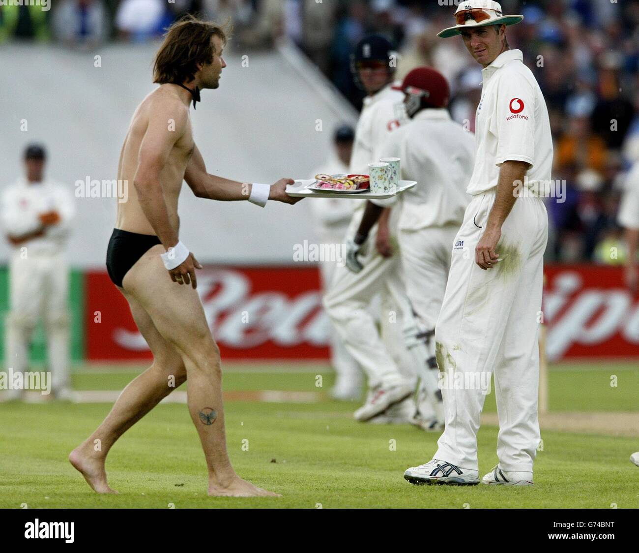 England captain Michael Vaughan looks at the streaker holding a tea tray, during the first day of the third npower test against West Indies at Old Trafford, Manchester. Stock Photo