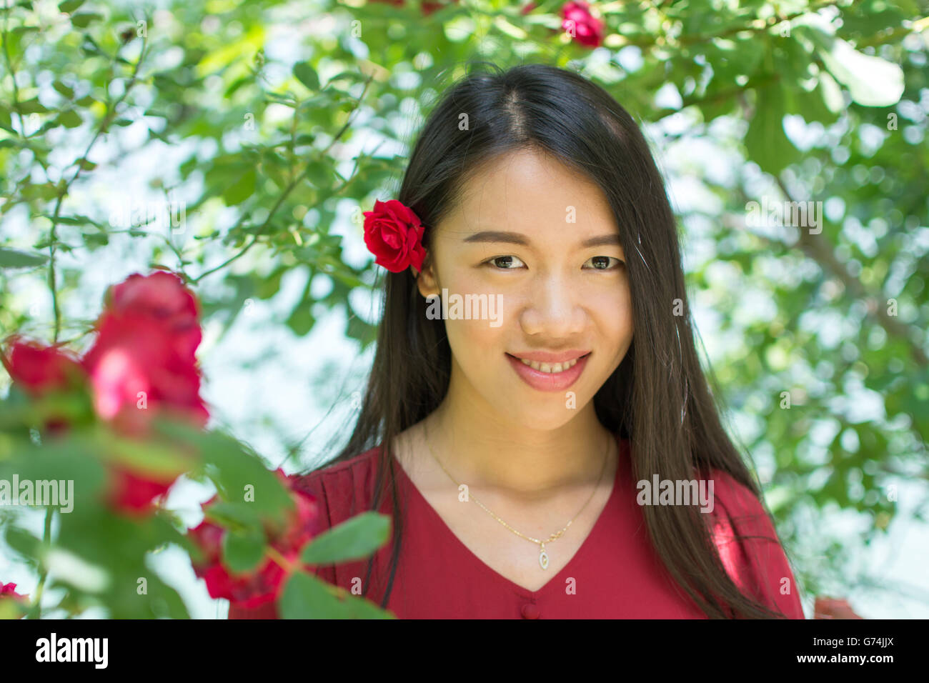 Woman in red dress with a red rose in her hair Stock Photo