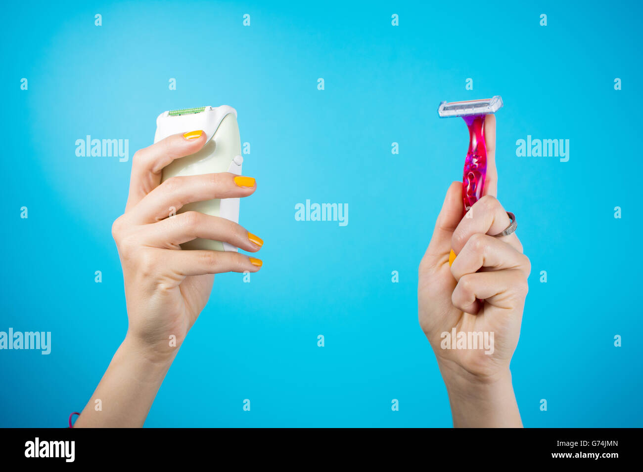 Red shaver and epilator in woman hand. Electric vs manual shave Stock