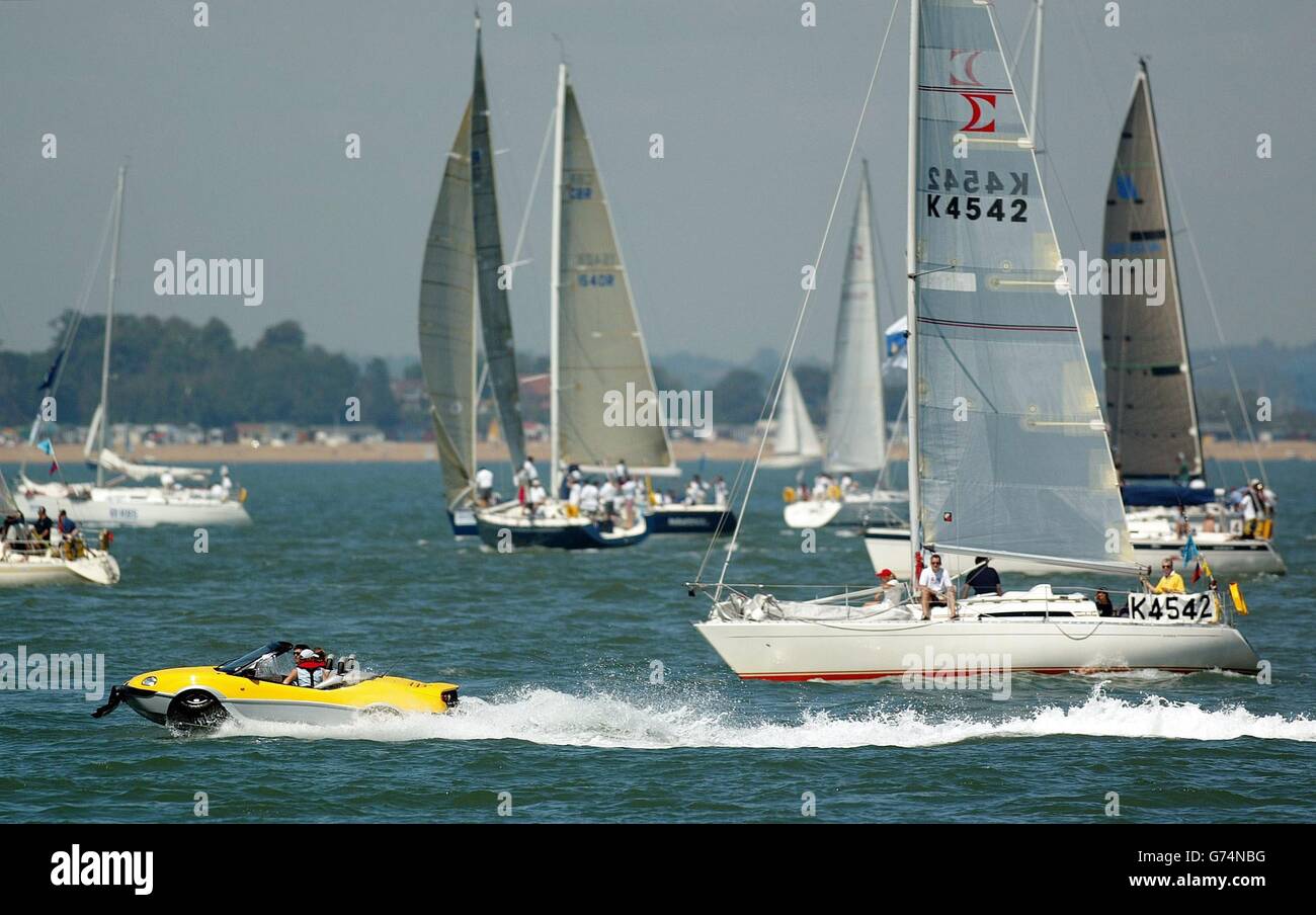 An amphibious car races past yachts on the Solent, on the first day of Skandia Cowes Week, the oldest and largest sailing regatta in the world. Stock Photo