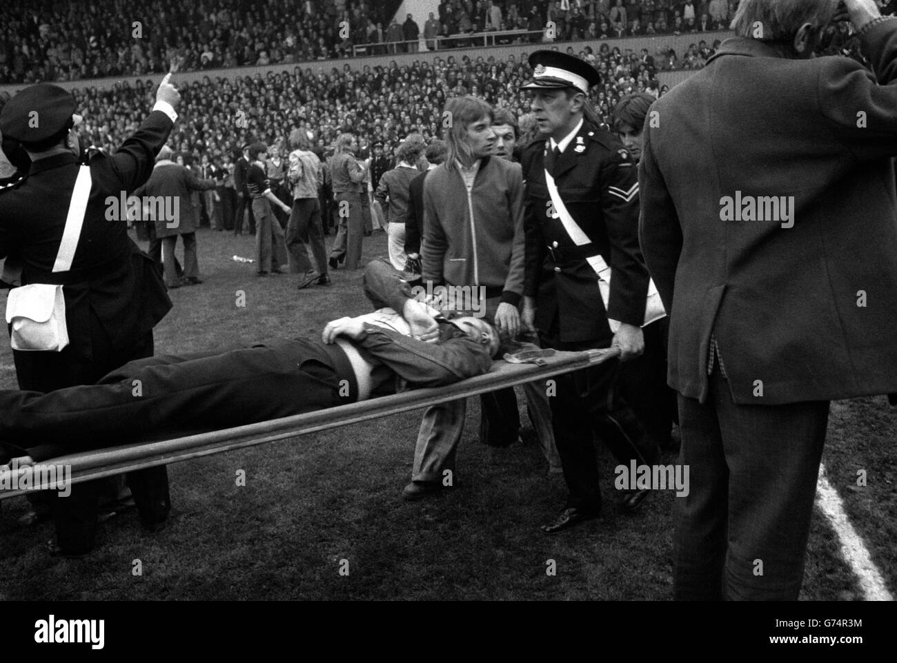 Ambulancemen are busy among the fans on the field at Upton Park, London, as fighting on the terraces and invasion of the pitch by spectators halted play for 19 minutes during West Ham's match against Manchester United. Stock Photo