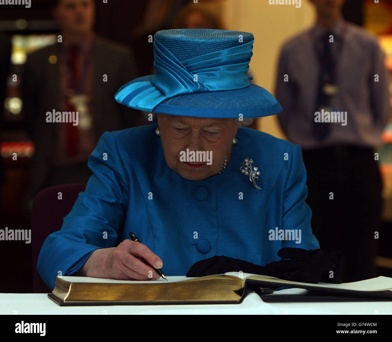 Queen Elizabeth II signs the new visitors book, at the official opening of the new Terminal 2 The Queen's Terminal at Heathrow Airport. Stock Photo