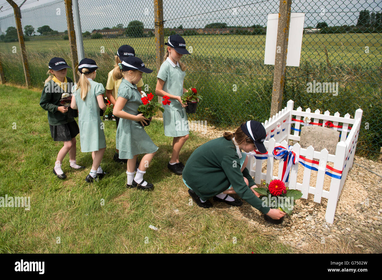 Children from Kempsford Primary School, put the finishing touches to the newly restored gravestone at RAF Fairford of Red Arrows mascot dog Dusty, who was owned by Henry Prince, a member of the first ever Red Arrows Team. Stock Photo