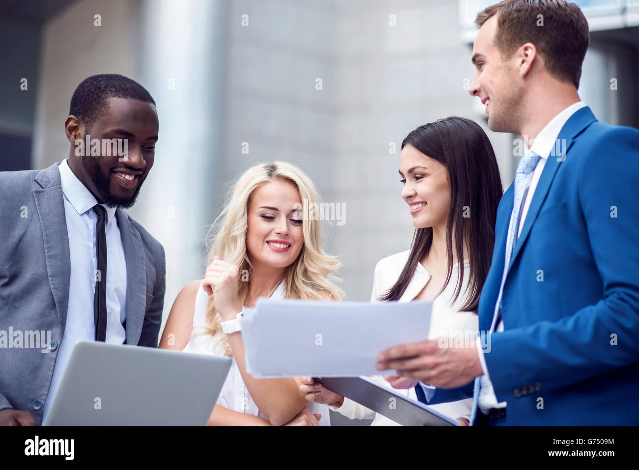 Positive colleagues standing near office building Stock Photo - Alamy