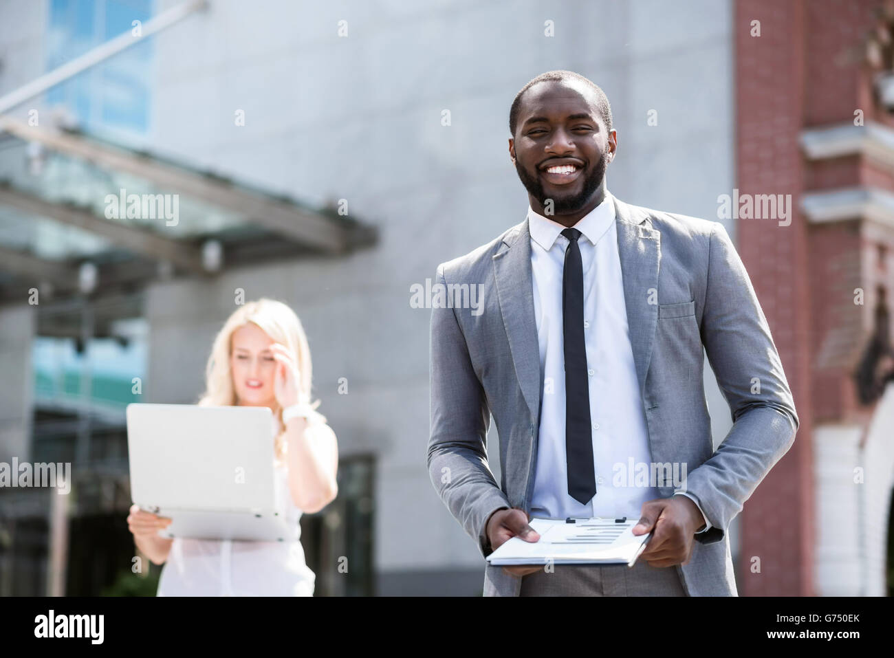 Handsome smiling man standing near office building Stock Photo - Alamy