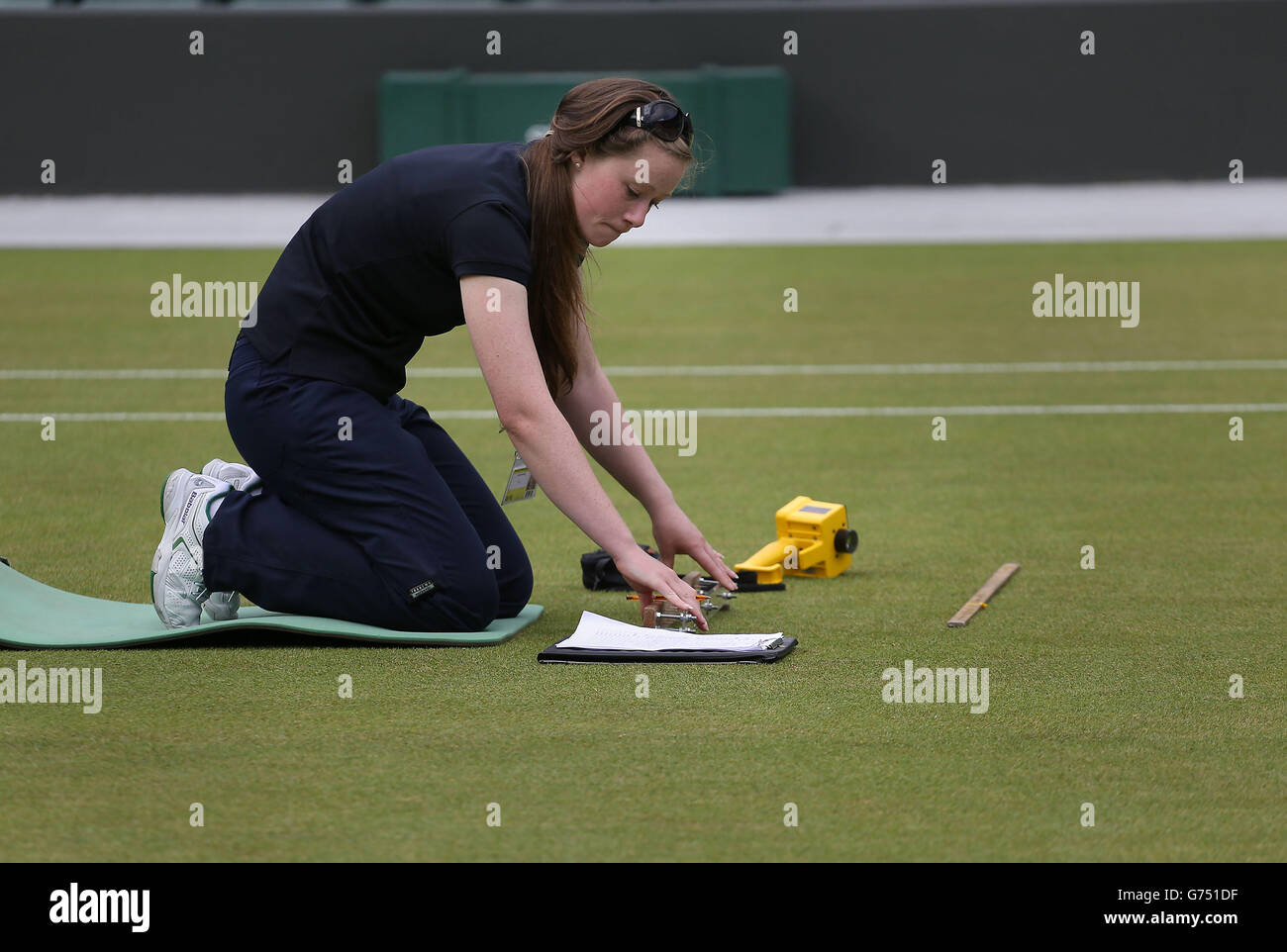 Laura Budimir, a research officer for the Sports Turf Research Institute checks live grass cover on Court 1 on day six of the Wimbledon Championships at the All England Lawn Tennis and Croquet Club, Wimbledon. Stock Photo